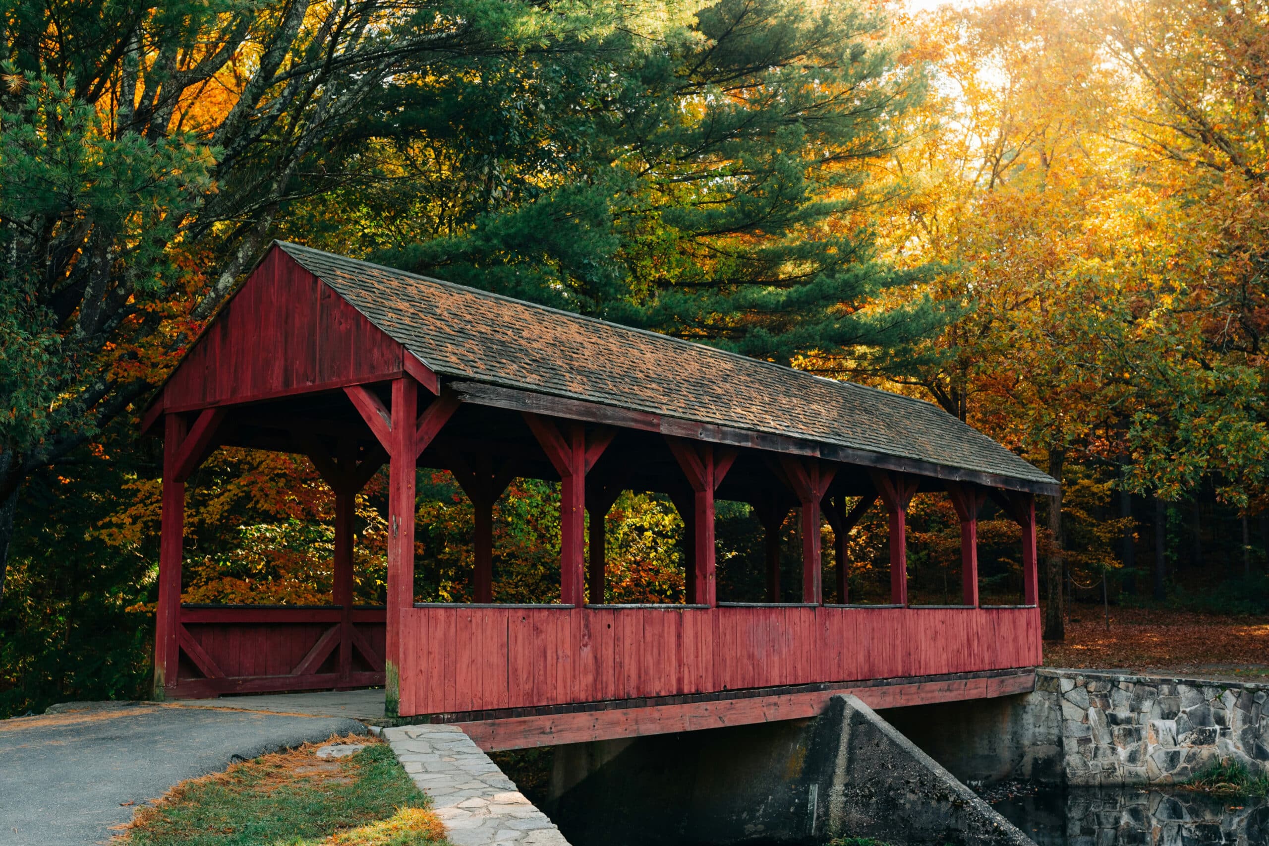 red wooden covered bridge over river in woods, charity auction travel packages, vacation fundraising, travel fundraising, fundraising ideas, charity ideas, silent auction items, travel fundraising events